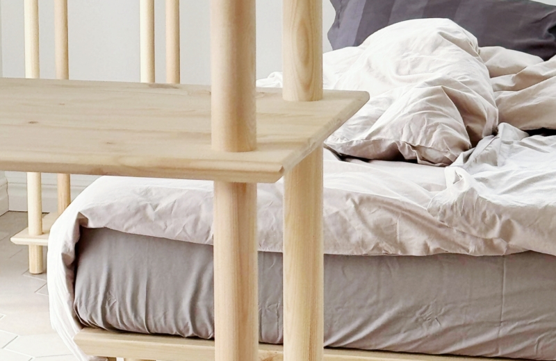 Close-up of natural pine wood Air Shelf System in a minimalist bedroom with the Air Bed 160x200 cm in the background, showing sustainable Nordic design and modular shelving