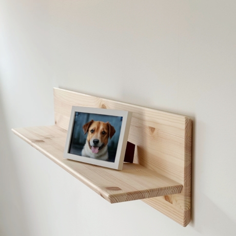 Étagère murale Air en pin clair non traité de 50 cm de largeur, montée sur un mur blanc, exposant une photo encadrée d’un chien brun et blanc souriant.