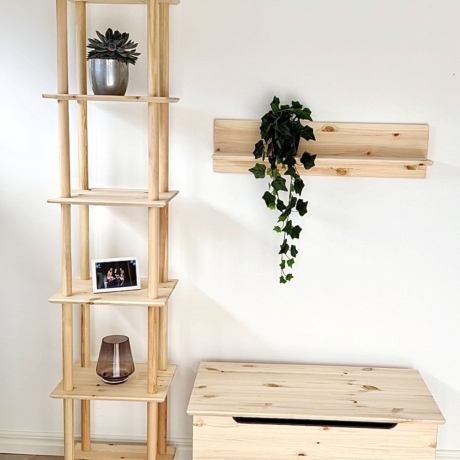 Vue d’ensemble de la pièce mettant en scène la grande étagère Air à six niveaux en pin brut, une étagère murale assortie avec du lierre, un banc de rangement en bois et un lit à la literie simple, l’ensemble contribuant à un intérieur minimaliste et cohérent.