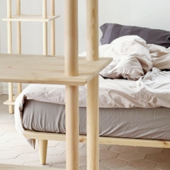 Gros plan du système d’étagères Air en pin naturel dans une chambre minimaliste, avec le lit Air 140 × 200 cm en arrière-plan, mettant en valeur le design nordique durable et les étagères modulaires.