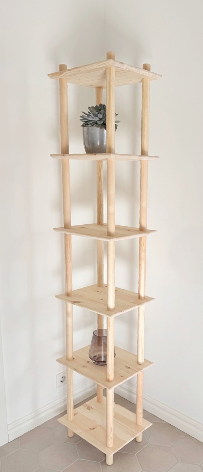 Full-height lifestyle shot of the raw pine Air Shelf narrow six-tiered unit, standing neatly in a room corner, styled with a succulent plant and a brown glass vase.