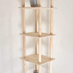 Full-height lifestyle shot of the raw pine Air Shelf narrow six-tiered unit, standing neatly in a room corner, styled with a succulent plant and a brown glass vase.