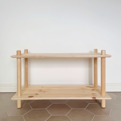 A wide, empty raw pine Air Shelf two-tiered modular unit is prominently displayed against a plain white wall and light hexagonal tiled floor, showcasing its clean design.