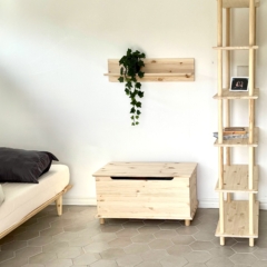 Full room shot featuring the raw pine Air Shelf narrow six-tiered unit, a matching wall shelf with ivy, a wooden storage bench, and a bed with grey bedding, all from the same collection.